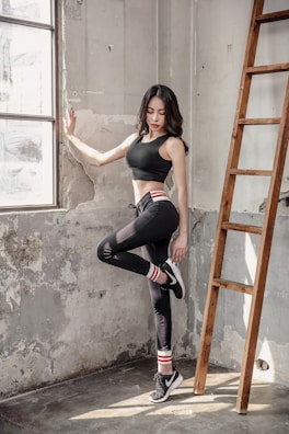 A casual gym athleisure outfit featuring a sleek crop top and leggings, captured mid-stretch in a sunlit studio.