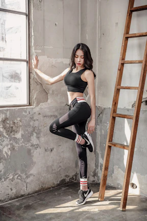 Confident woman tying sneakers beside yoga mat on wooden floor bathed in soft light.