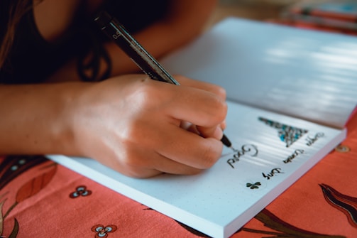 A learner writing vocabulary words on a notebook.