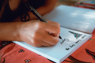 Close-up of hands writing Italian phrases on colorful notebooks during a lesson.