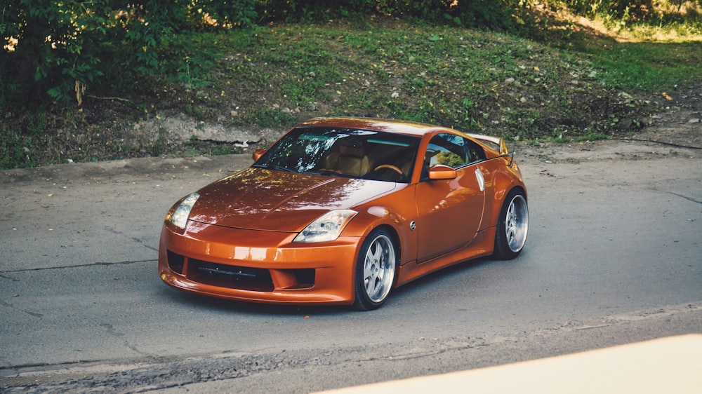 orange porsche 911 parked on gray asphalt road during daytime