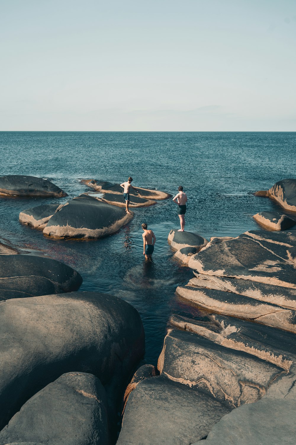 3 women in bikini on rocky shore during daytime