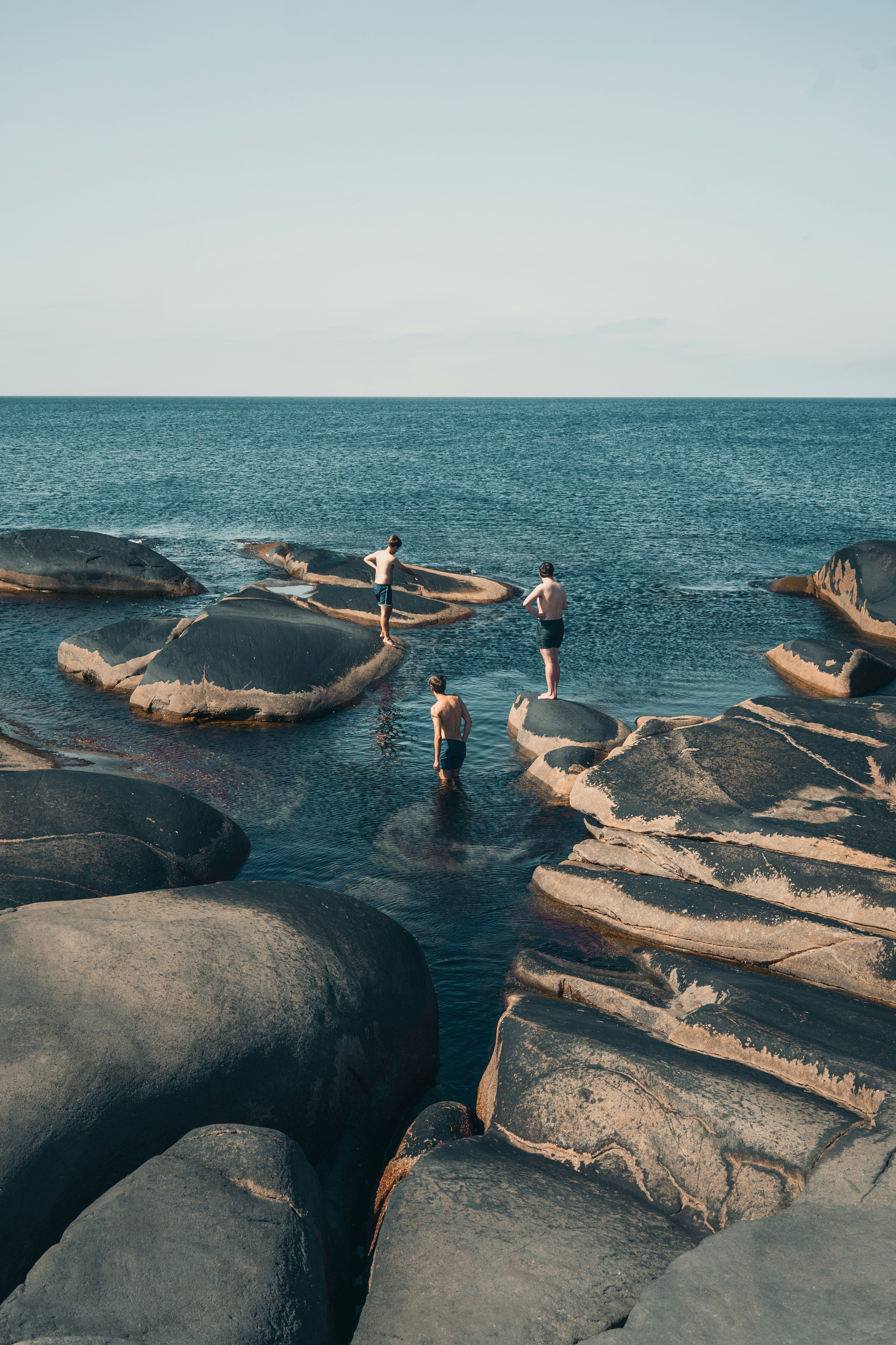 3 women in bikini on rocky shore during daytime