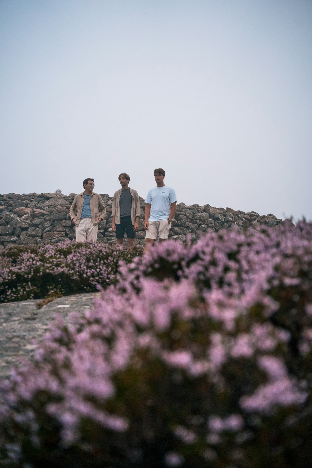 2 men standing on rocky hill during daytime