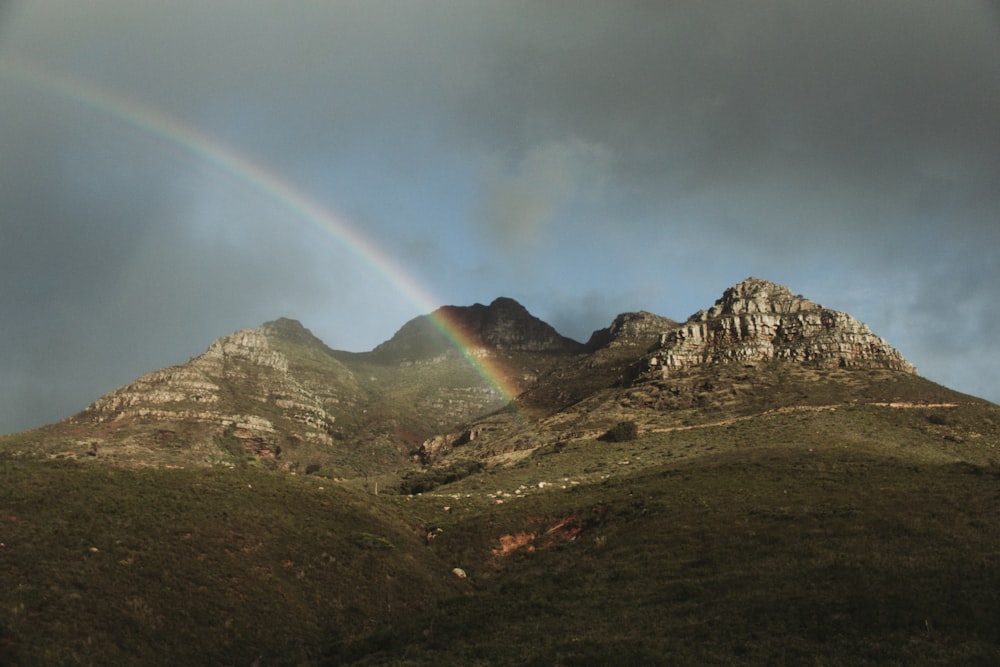 rainbow over brown and green mountain