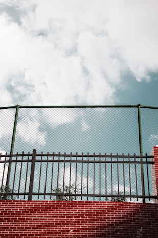 A close-up of a sturdy vinyl fence with a clear blue sky in the background.