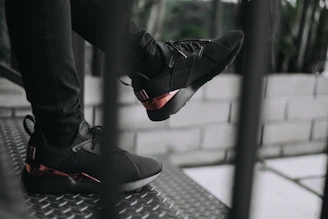 Close-up of matte black sneakers with electric red glow accents on a concrete stairwell.