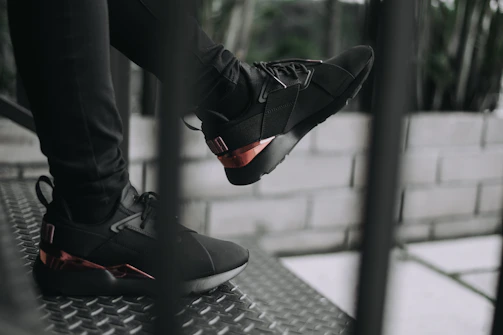 Close-up of matte black sneakers with electric red glow accents on a concrete stairwell.