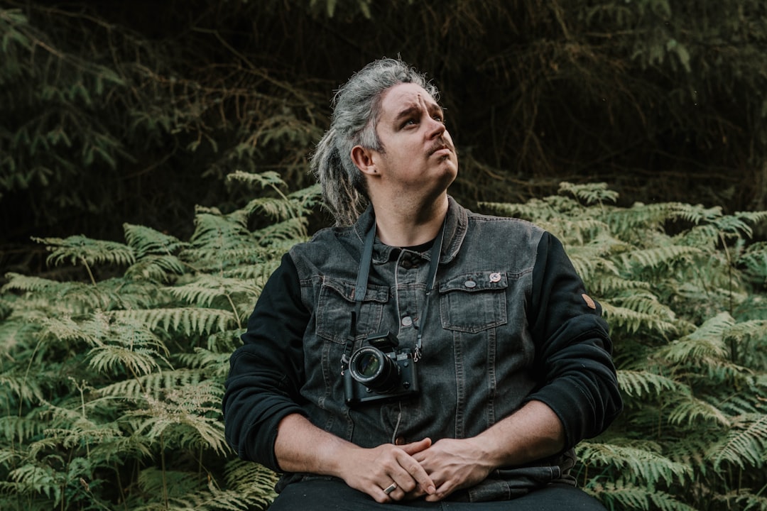 man in black jacket sitting on grass