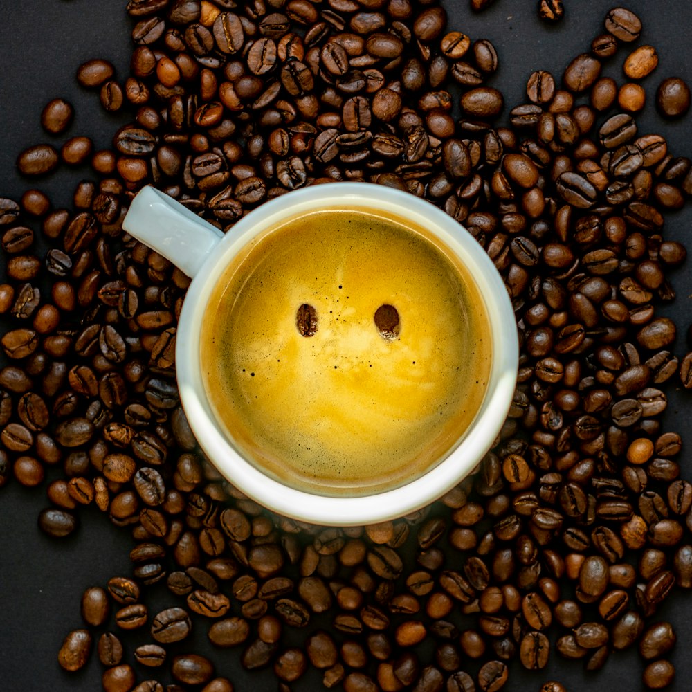 white ceramic mug on coffee beans