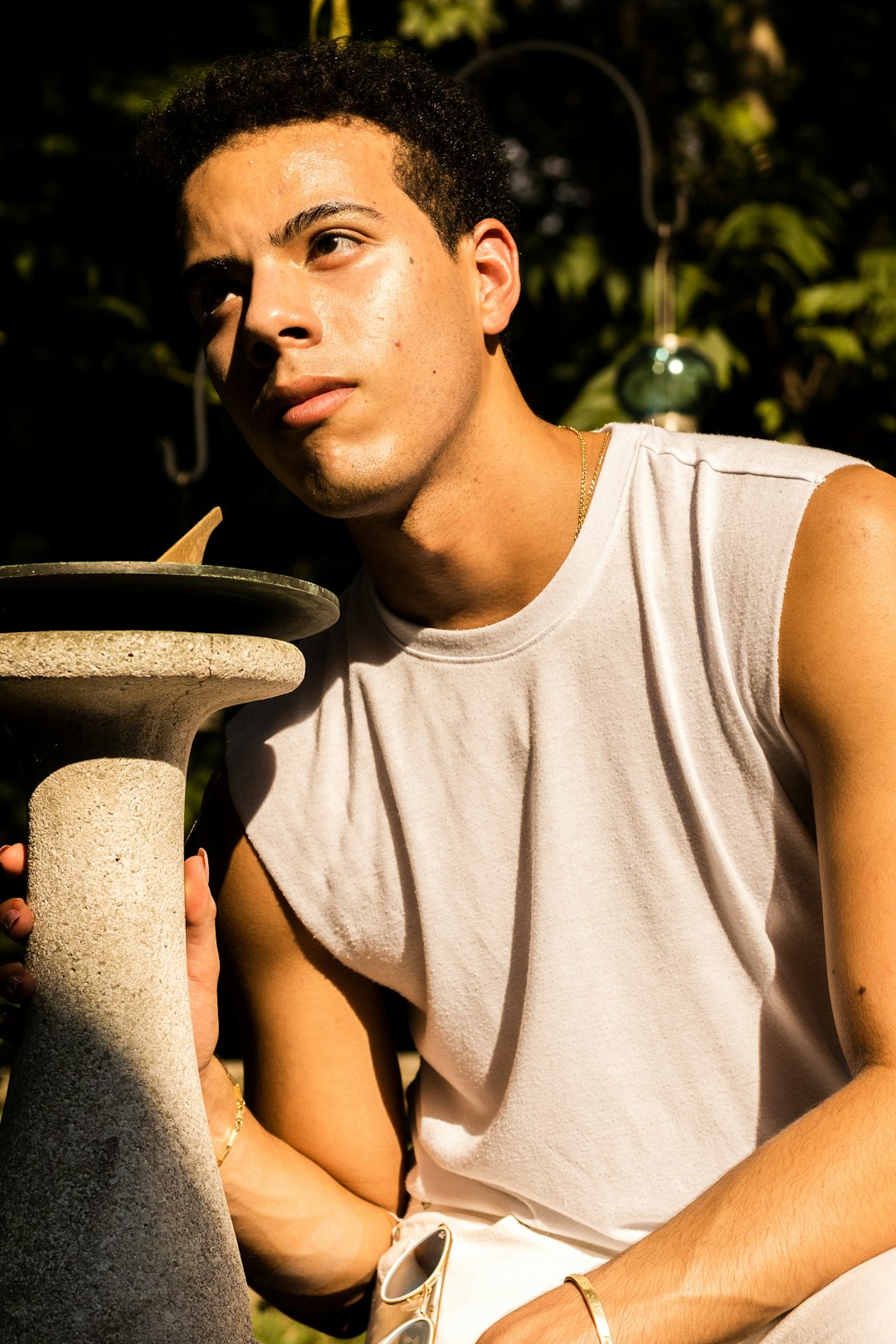 man in gray tank top holding brown round pot