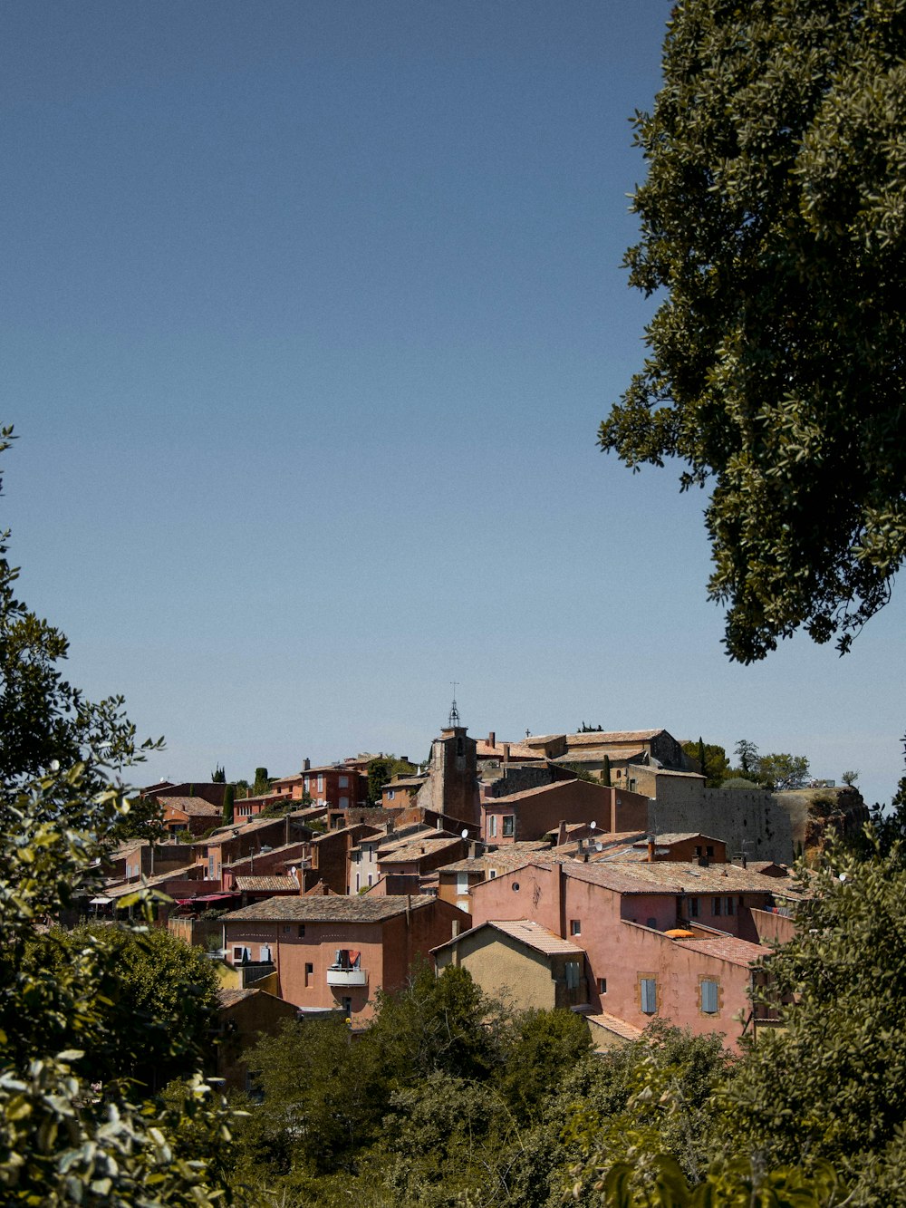 brown concrete houses near green trees under blue sky during daytime