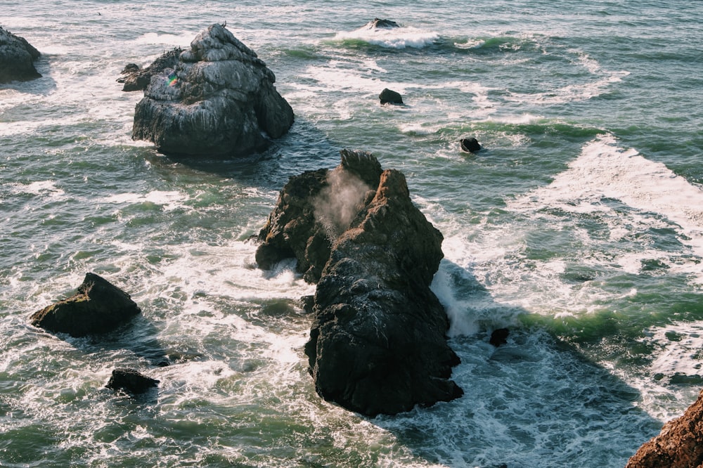 black rock formation on sea during daytime