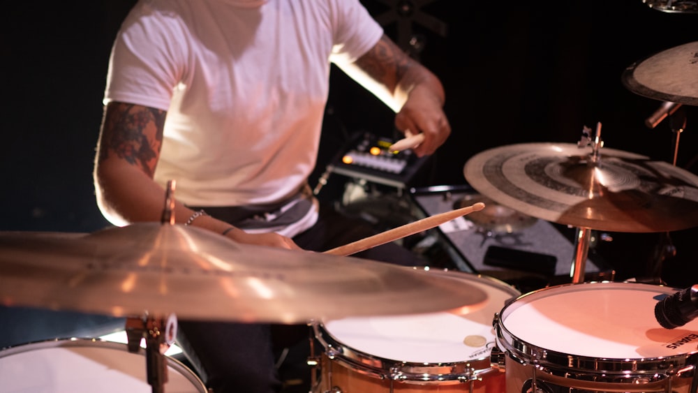 man in white t-shirt playing drum