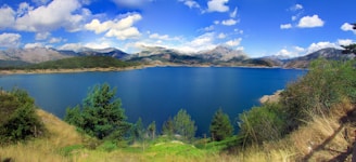 A serene lake surrounded by lush greenery and mountains.
