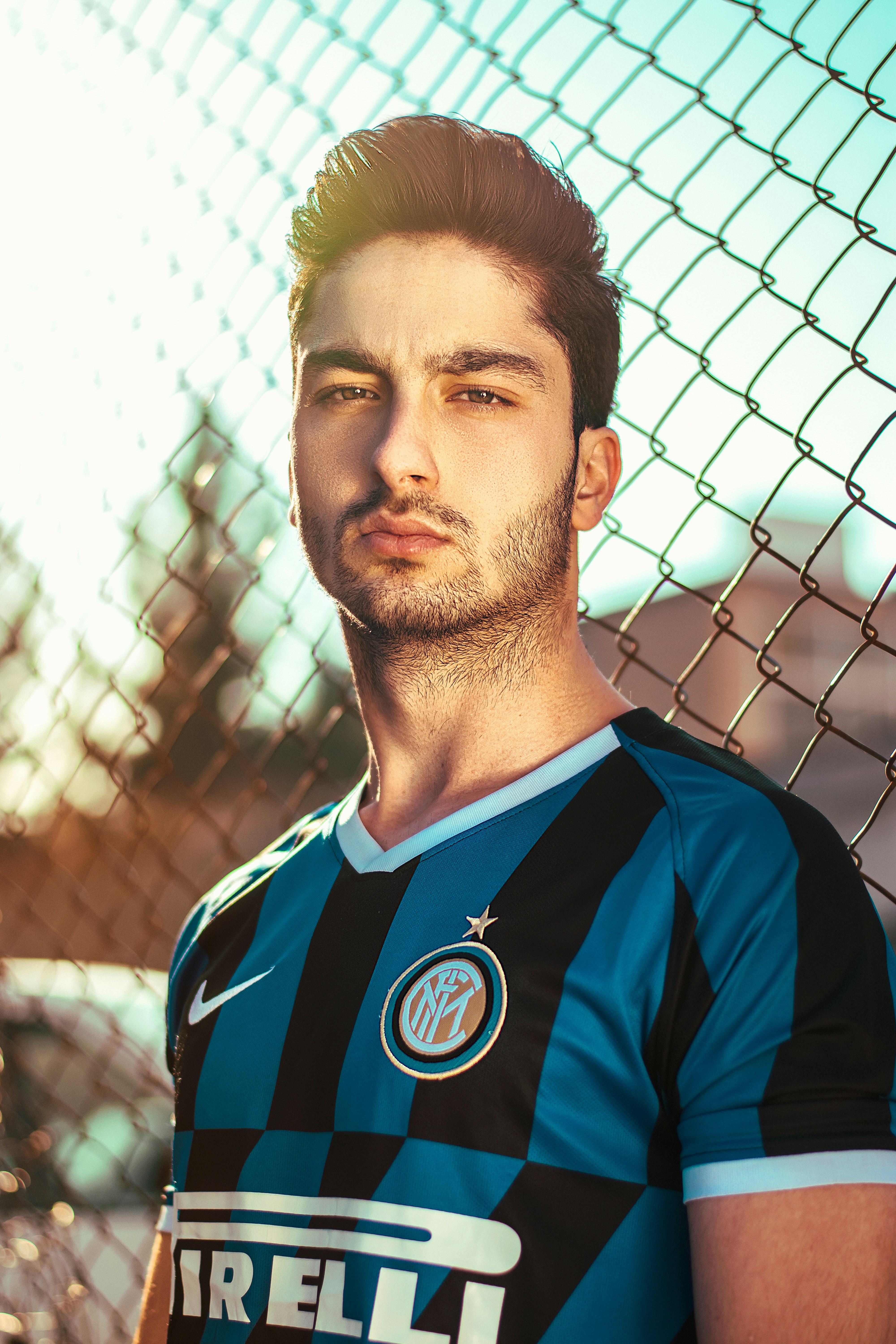 man in blue and red adidas jersey shirt standing near chain link fence