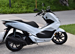 black and gray motor scooter parked on gray concrete road during daytime