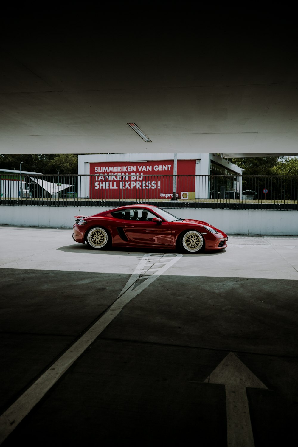 red coupe parked on gray concrete road