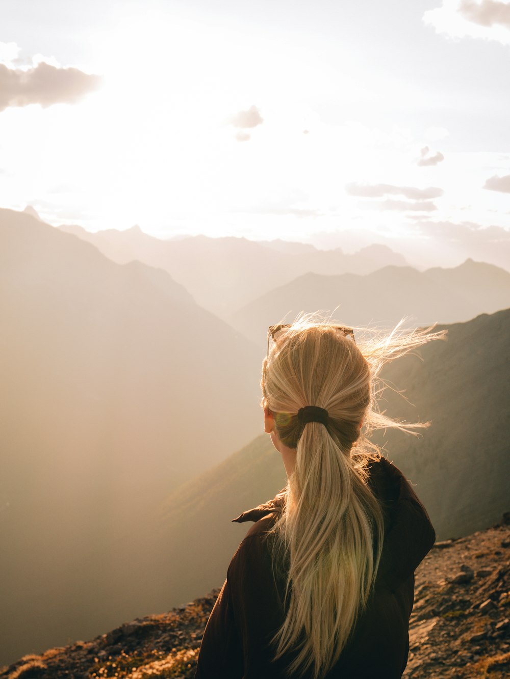 woman in gray shirt standing on rock near lake during daytime