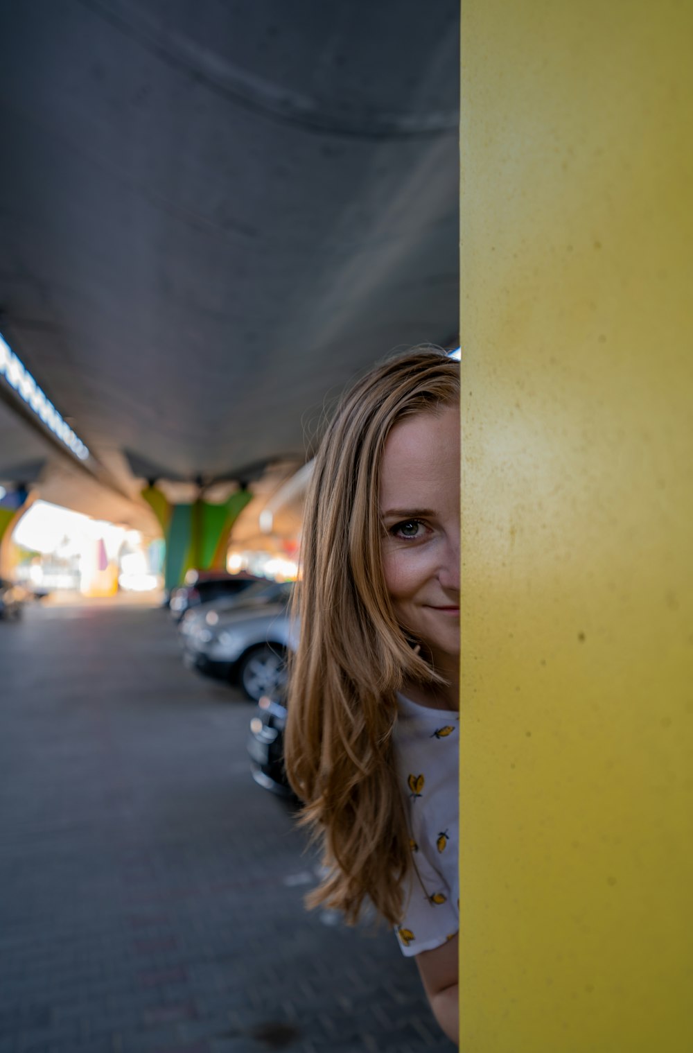 woman in white shirt leaning on yellow wall