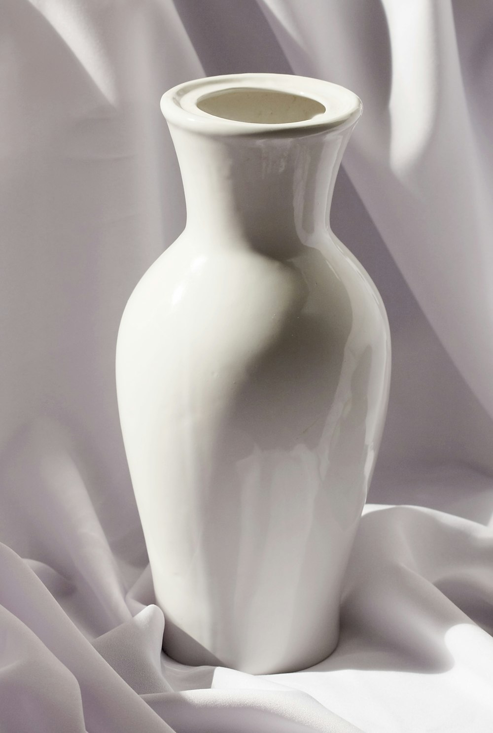 Vase en céramique blanche sur textile blanc