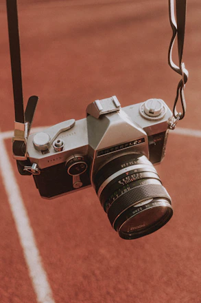 Close-up of a vintage film camera set against a backdrop of colorful festival banners.