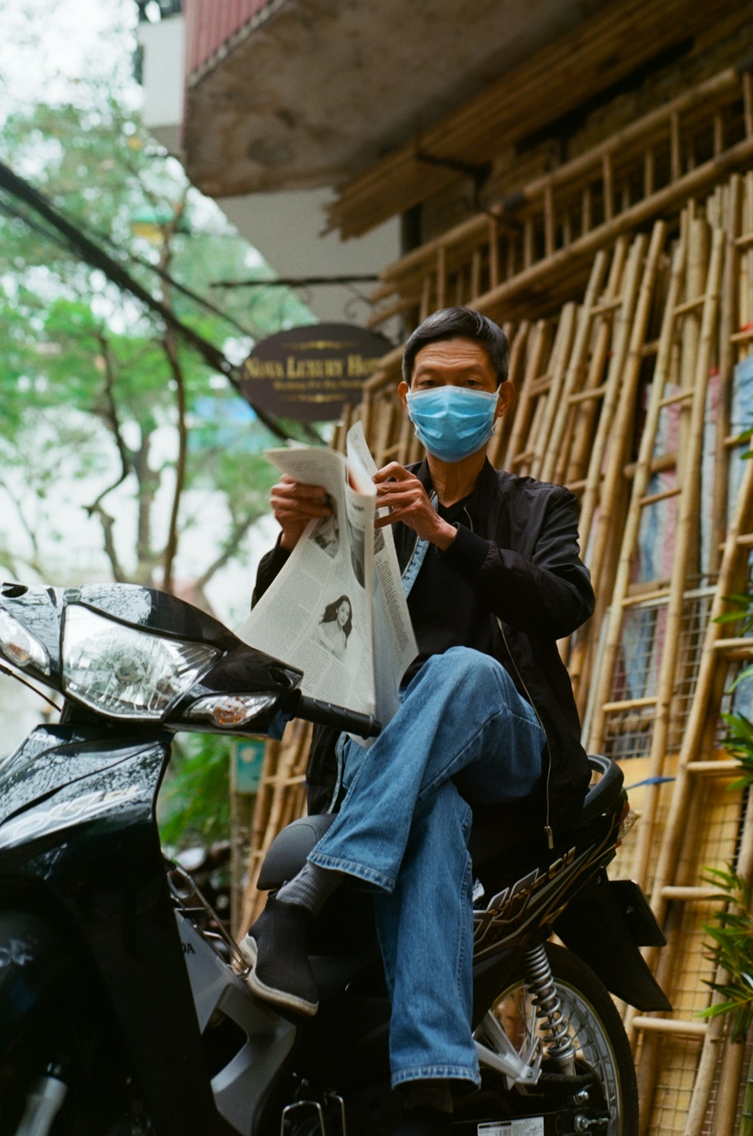 man in black jacket and blue denim jeans sitting on brown wooden bench