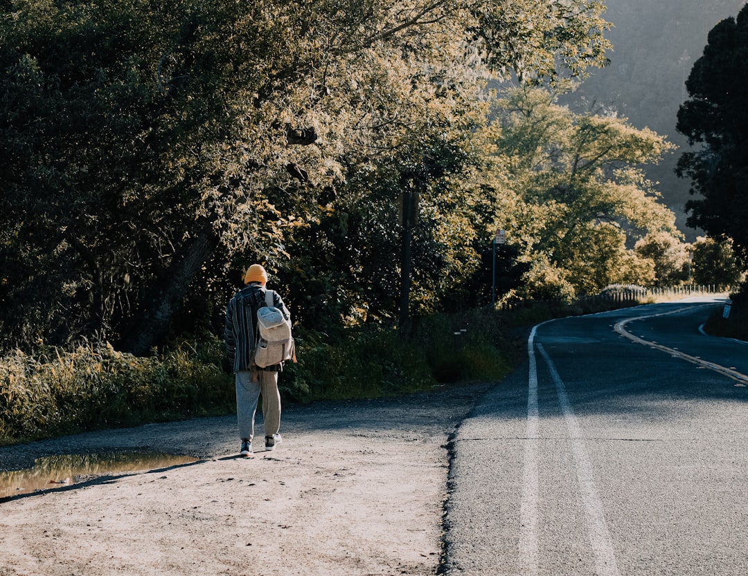 man in gray jacket and brown pants standing on gray asphalt road during daytime