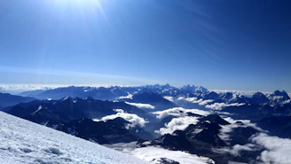 A wide scenic view of snow-capped mountains under a clear sky, with teal accents subtly enhancing the scene.