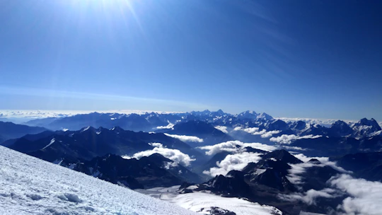 A wide scenic view of snow-capped mountains under a clear sky, with teal accents subtly enhancing the scene.