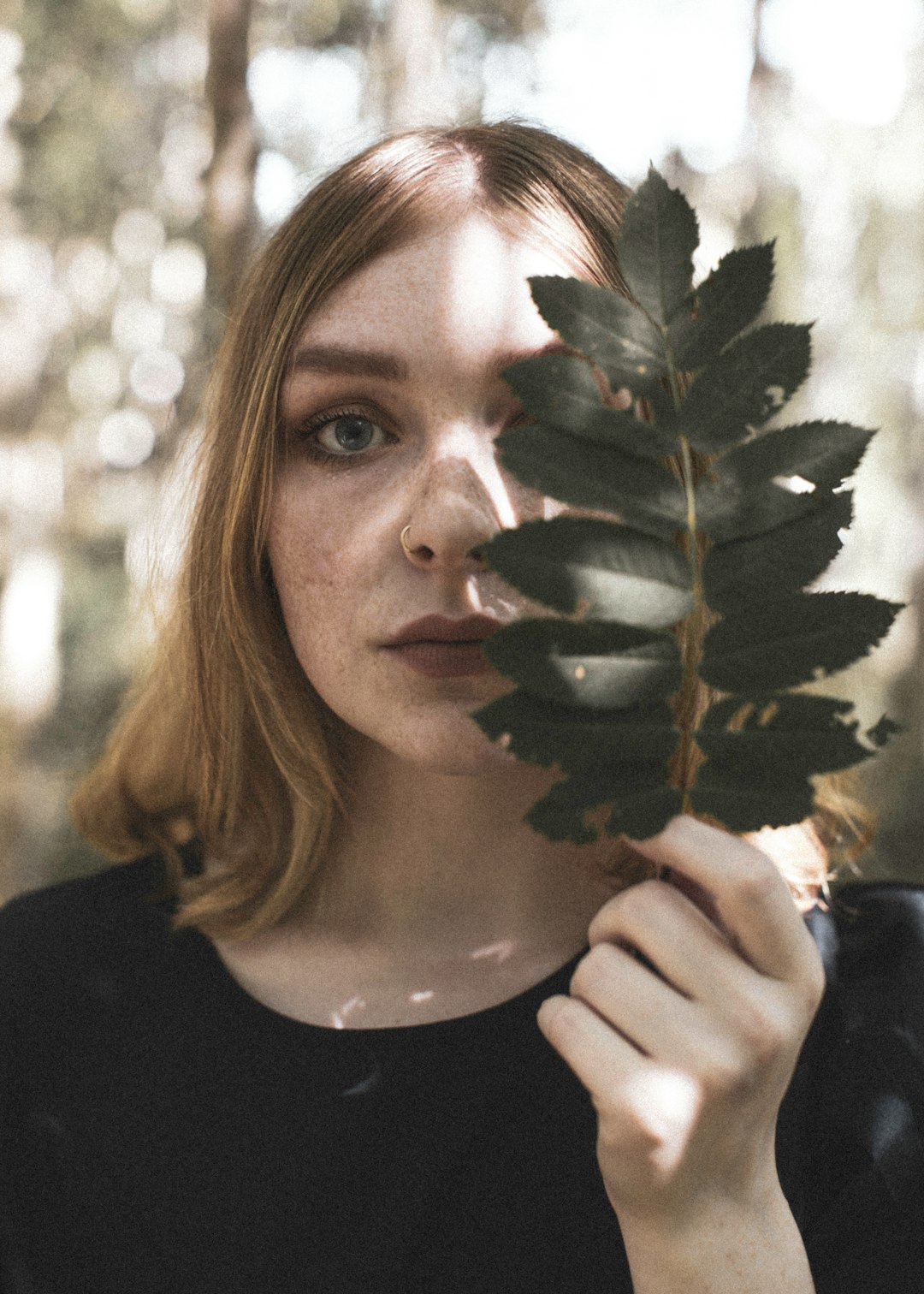 woman in black crew neck shirt holding green plant