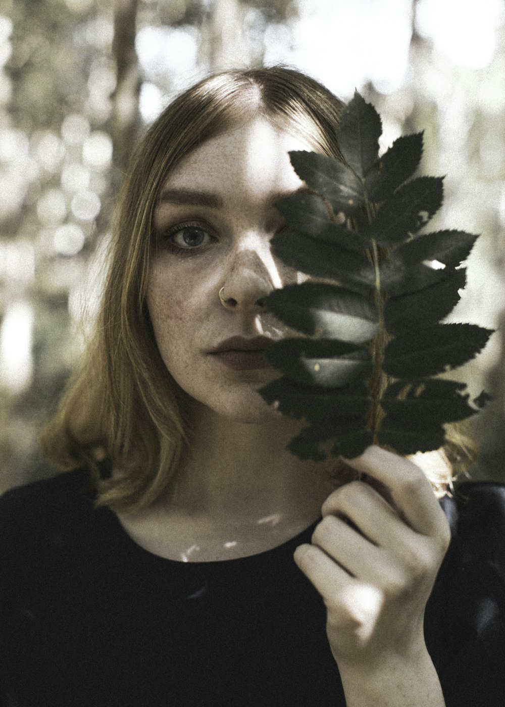 woman in black crew neck shirt holding green plant