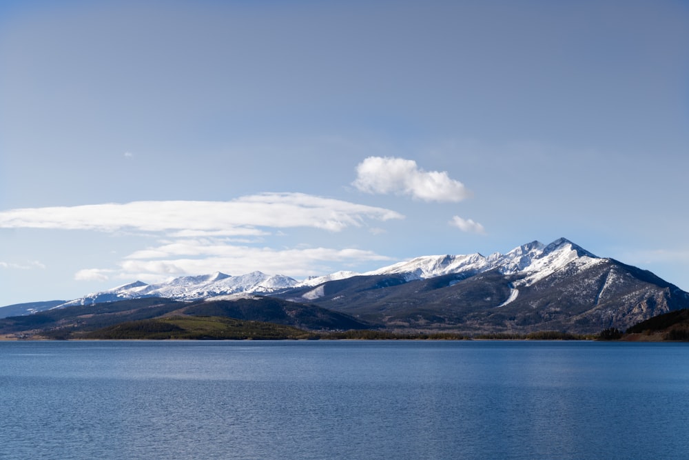 snow covered mountains near body of water during daytime