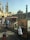 A street market scene featuring several stalls displaying various goods, including jewelry and souvenirs. Two individuals are seen browsing the merchandise. In the background, historic Islamic architecture with tall minarets and a dome can be observed, suggesting a culturally rich area.
