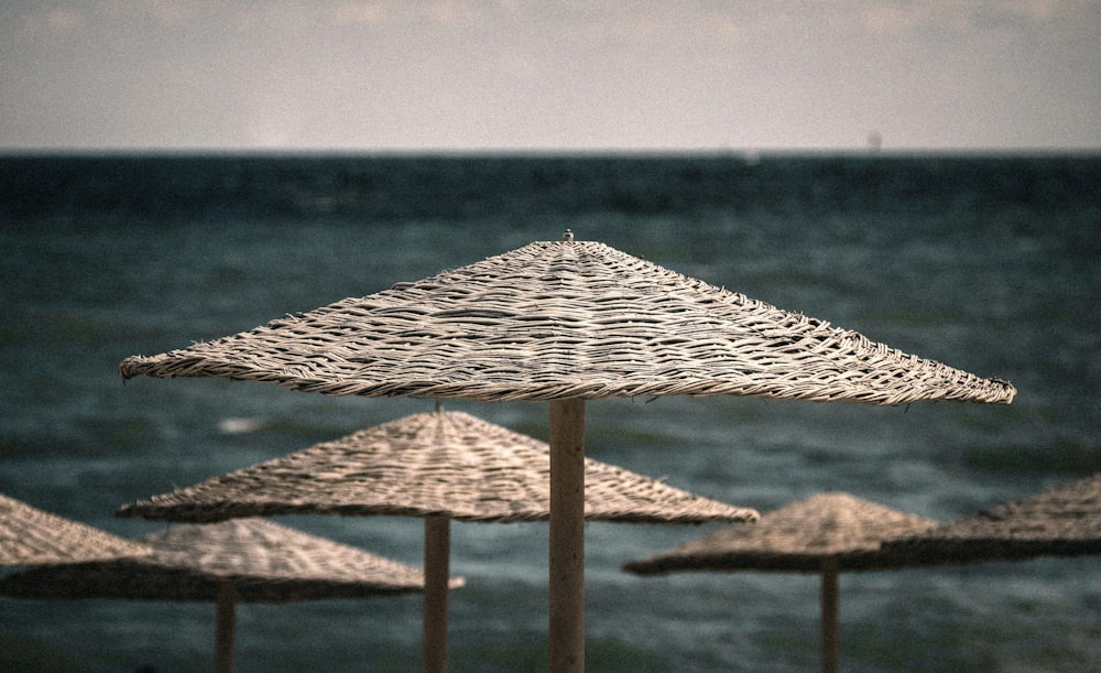 brown wooden beach umbrella on brown sand near body of water during daytime