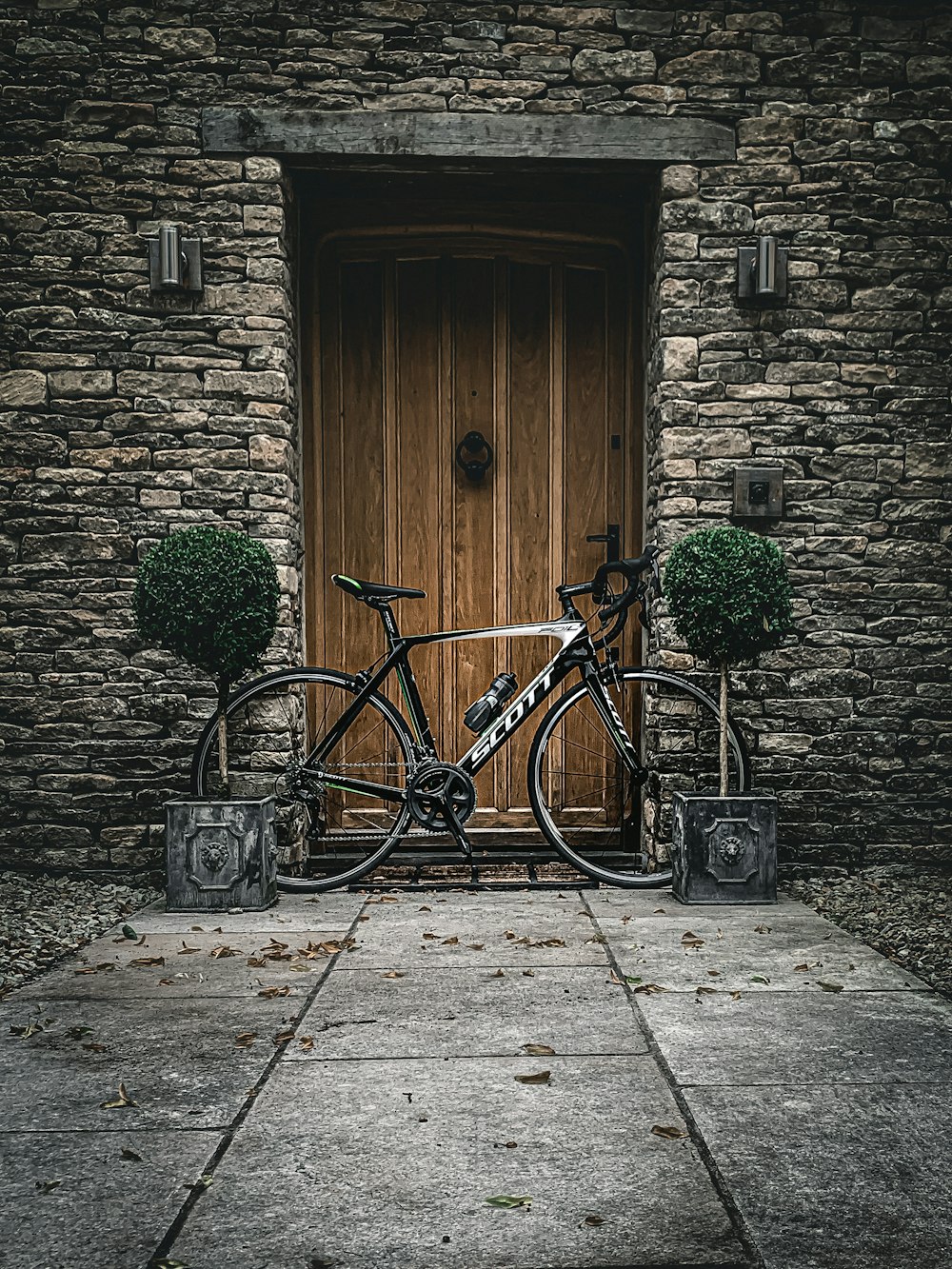 black city bike parked beside brown wooden door