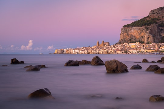 brown rock formation on sea during daytime in Cefalù Italy