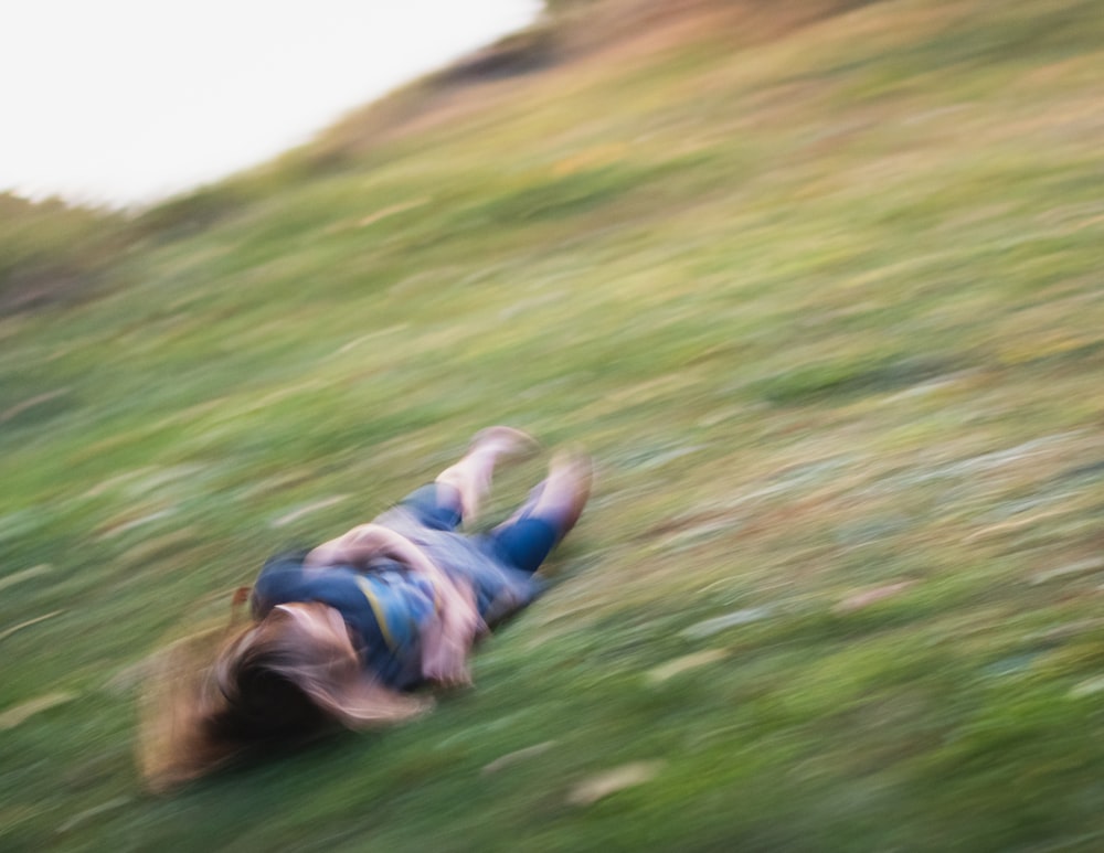 girl in blue jacket lying on green grass field during daytime
