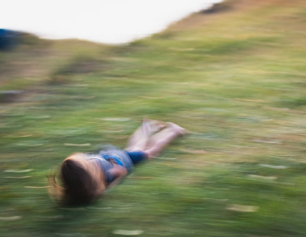 woman in white and blue stripe shirt lying on green grass field during daytime