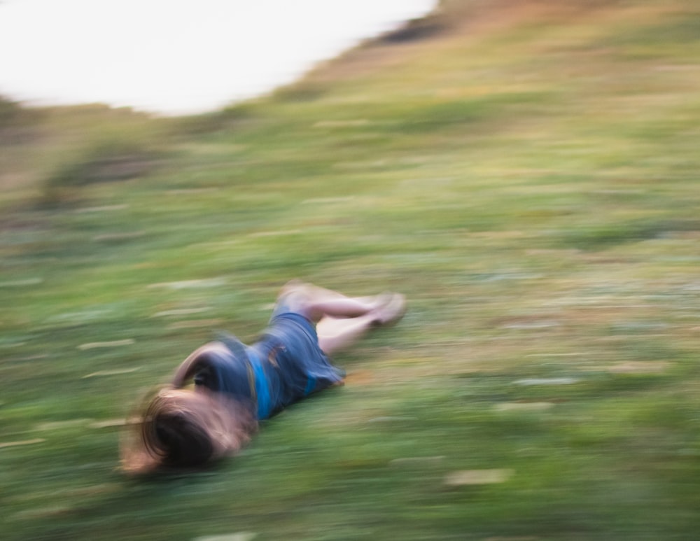 donna in camicia verde sdraiata sul campo di erba verde durante il giorno