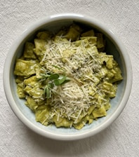 A bowl of fresh pasta with herbs and a sprinkle of cheese.