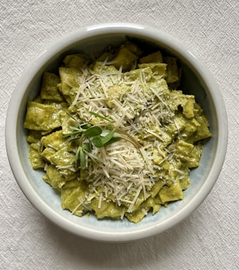 A bowl of fresh pasta with herbs and a sprinkle of cheese.