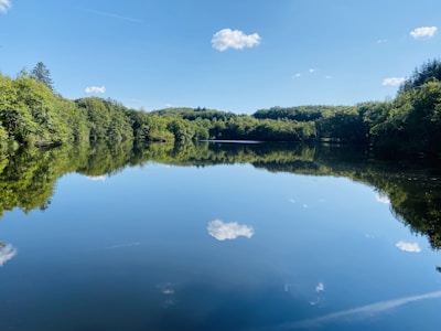 A serene lake reflecting the sky, surrounded by trees.