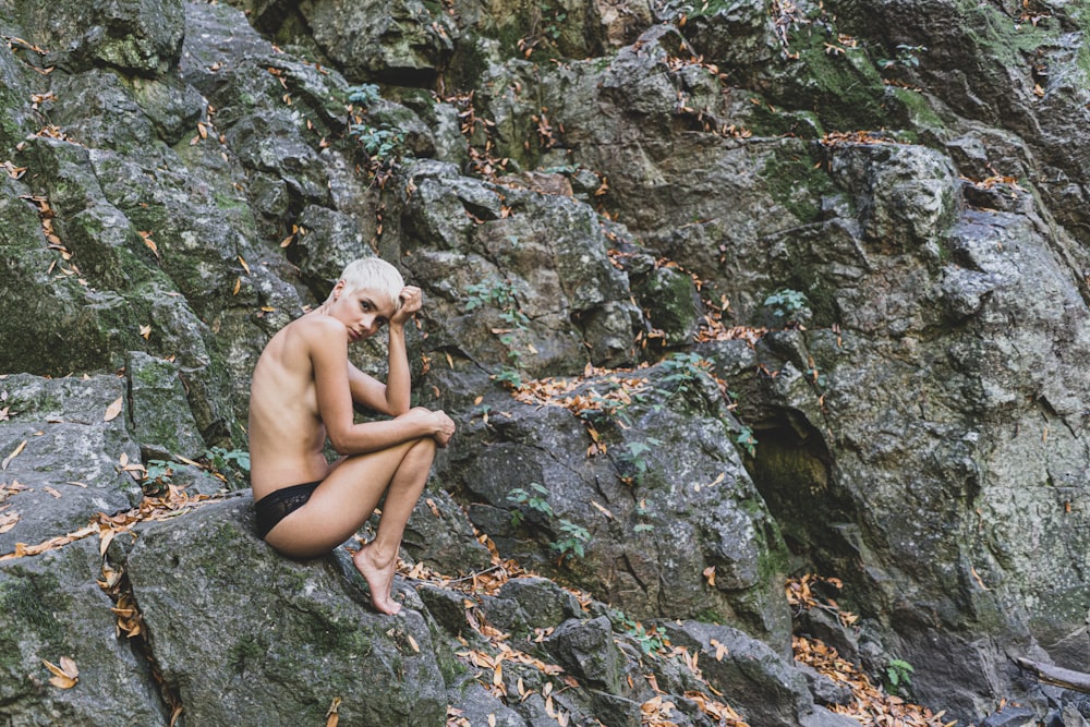 岩の上に座っている黒いビキニの女性