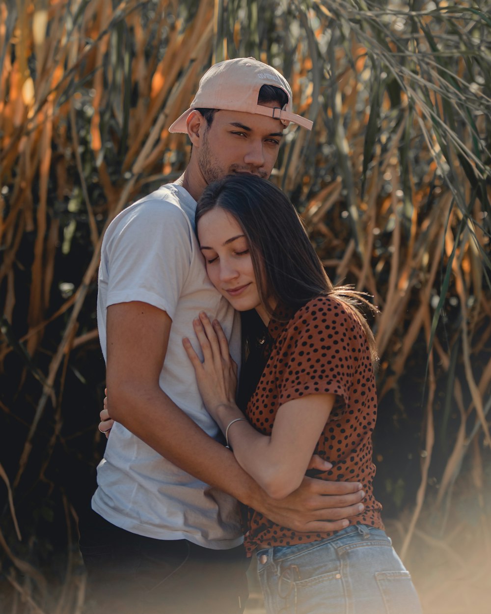 man in white crew neck t-shirt hugging woman in brown and black leopard print sleeveless