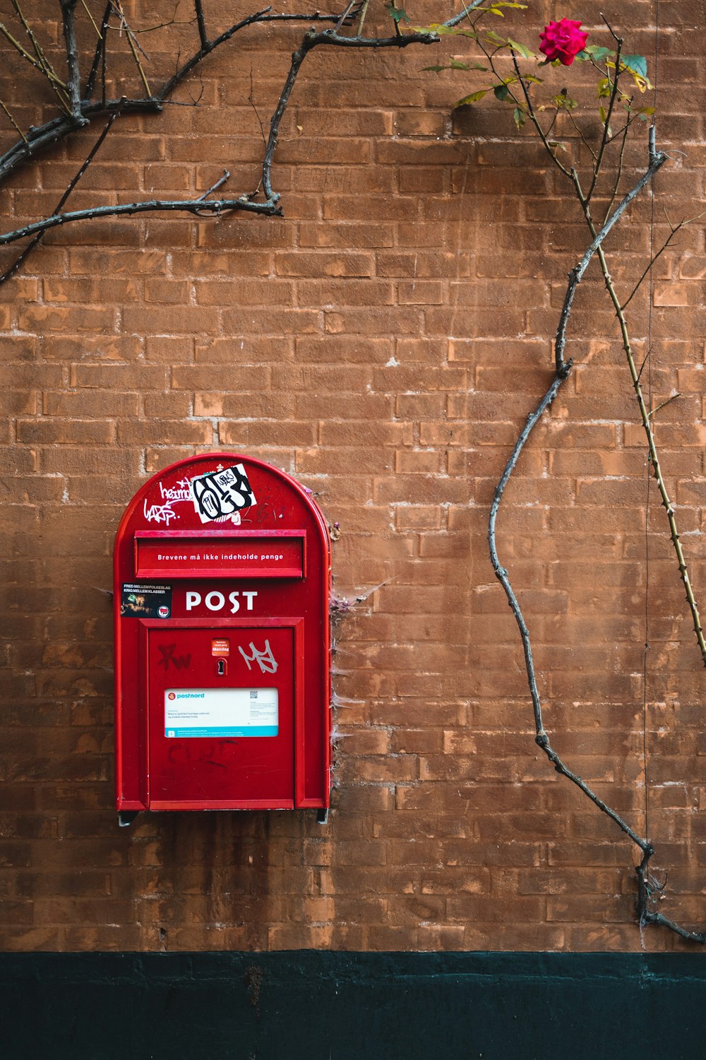 red mail box mounted on brown brick wall