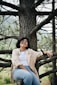 woman in white dress shirt sitting on brown tree branch during daytime