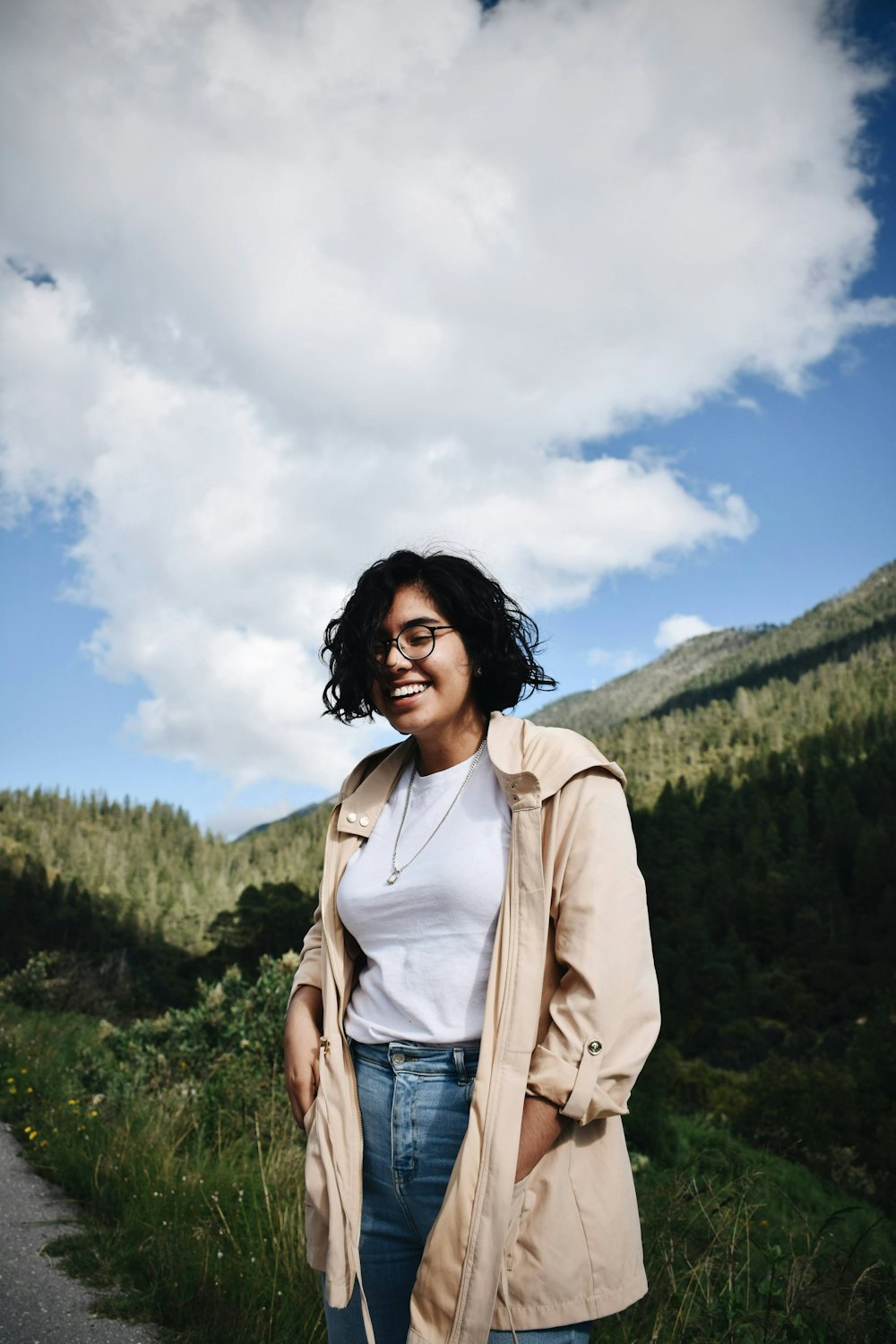 woman in beige jacket standing on mountain under white clouds during daytime