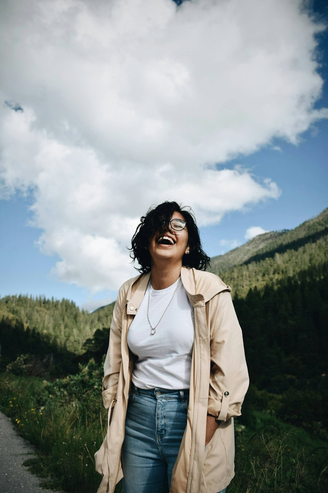 woman in beige jacket standing on mountain under white clouds during daytime