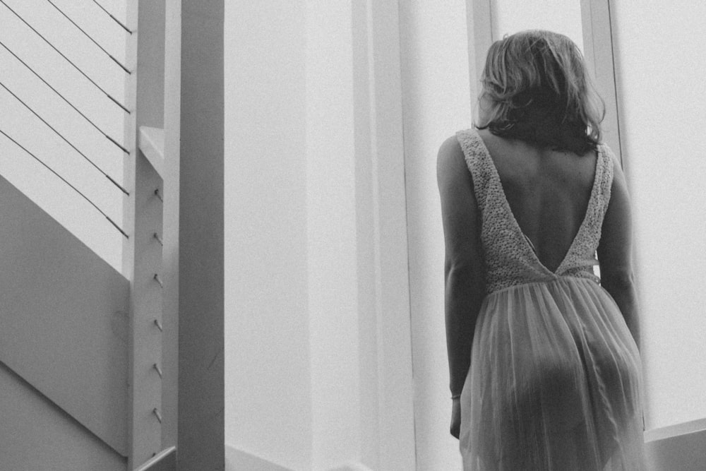 woman in white tank top standing near white wall